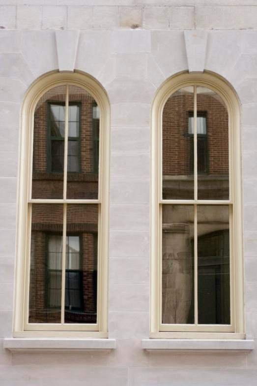 Pair of arched double-hung wood windows in a cream facade