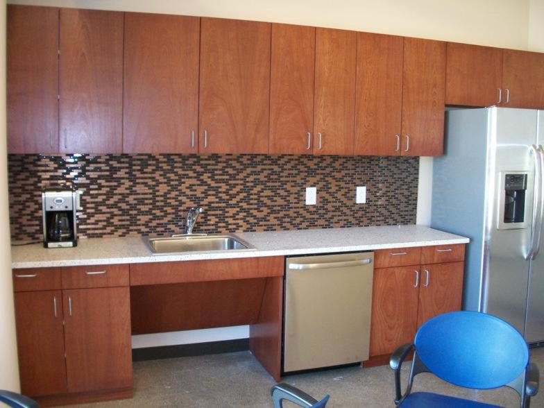 Cherry-finish kitchen cabinetry with mosaic backsplash in an office break room