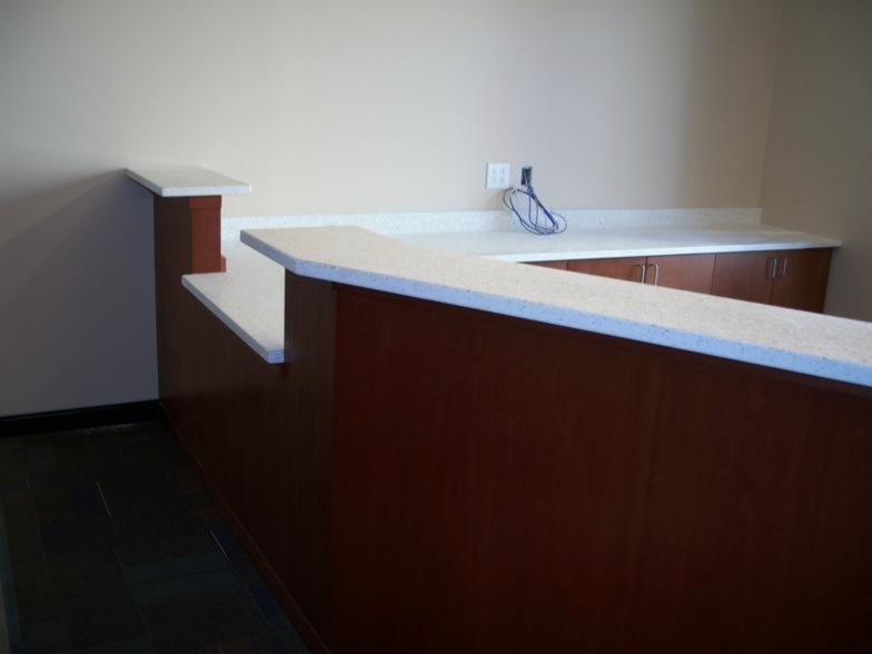 L-shaped wood reception desk with solid surface transaction counter